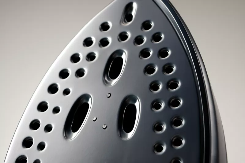 Detalle de la suela cerámica de una plancha de vapor con orificios de salida de vapor